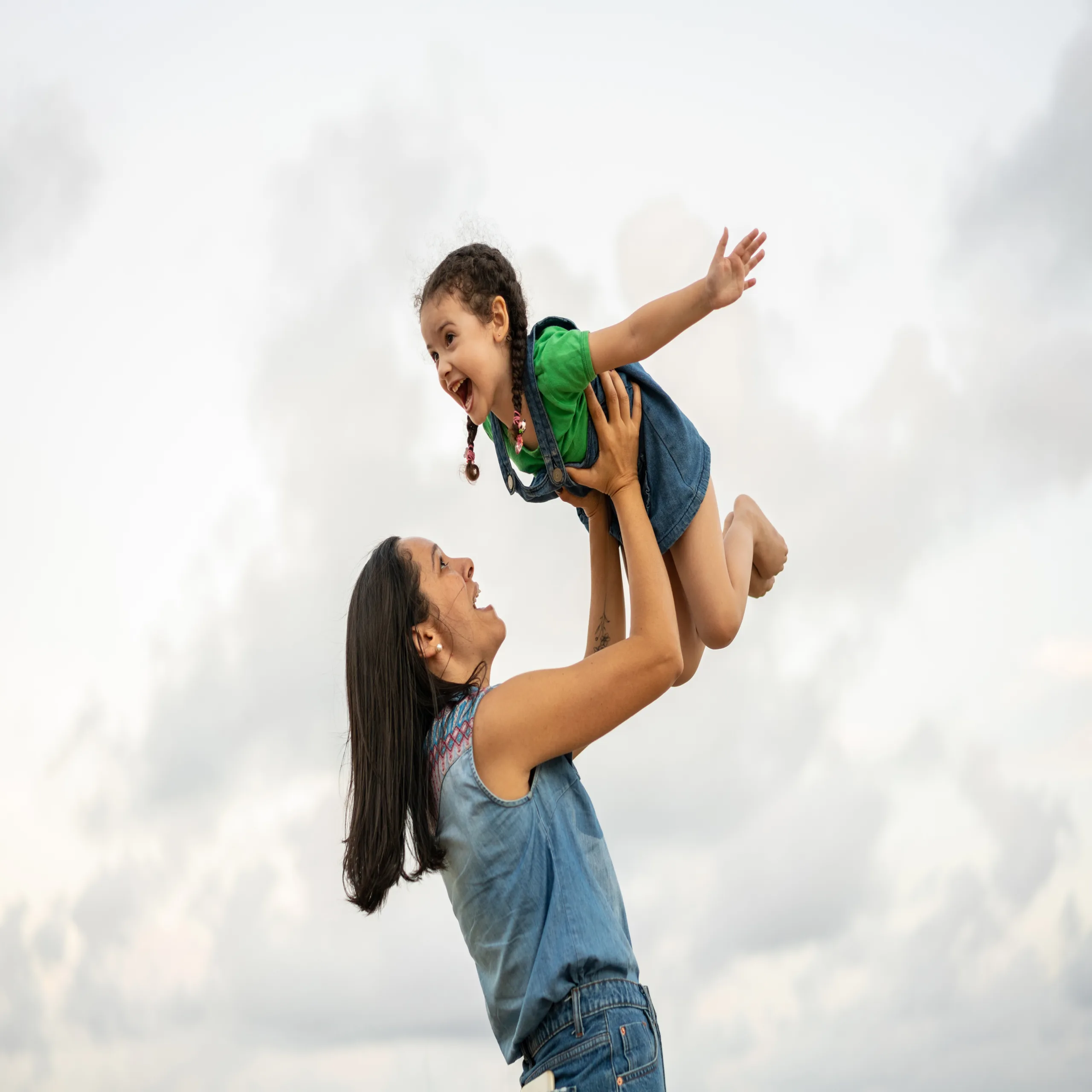 Little girl playing airplane in her mother's arms