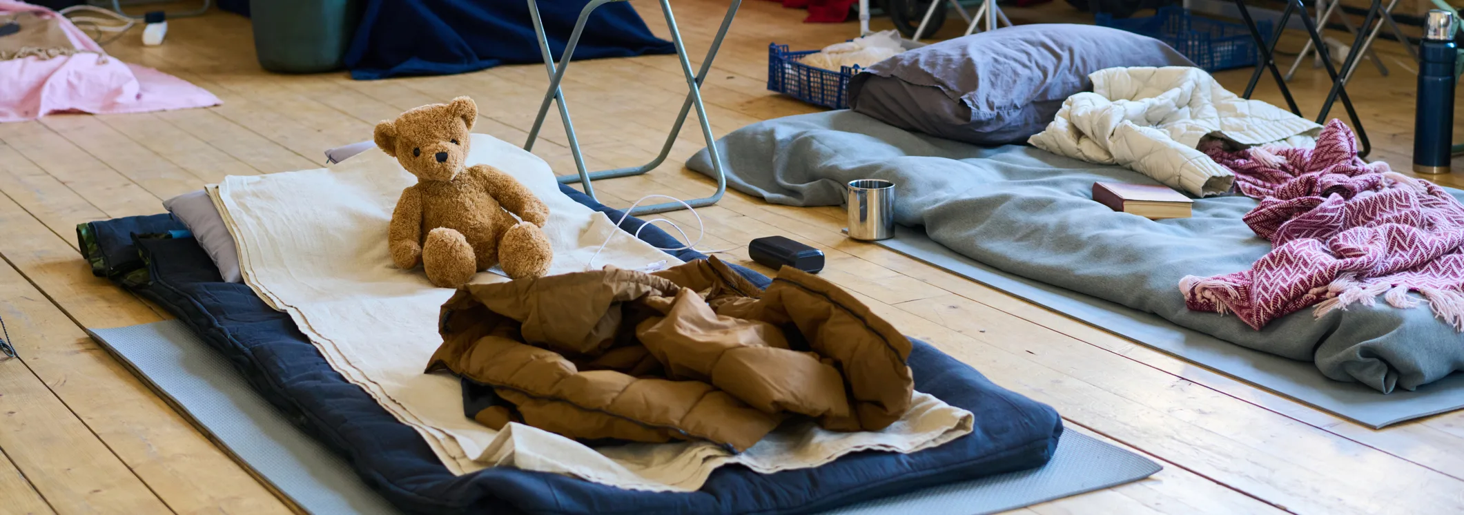 Part of spacious room with sleeping places on wooden floor for refugees