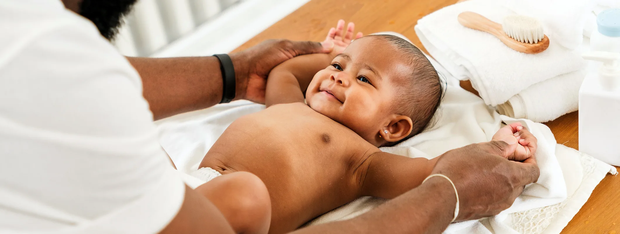 African father lovingly plays with his smiling newborn daughter during baby care time, celebrating joyful fatherhood moments and bonding in a warm, natural light home setting.